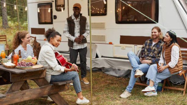 Two scenes of people near a camper van; one with two people sitting, the other with two people at a picnic table.